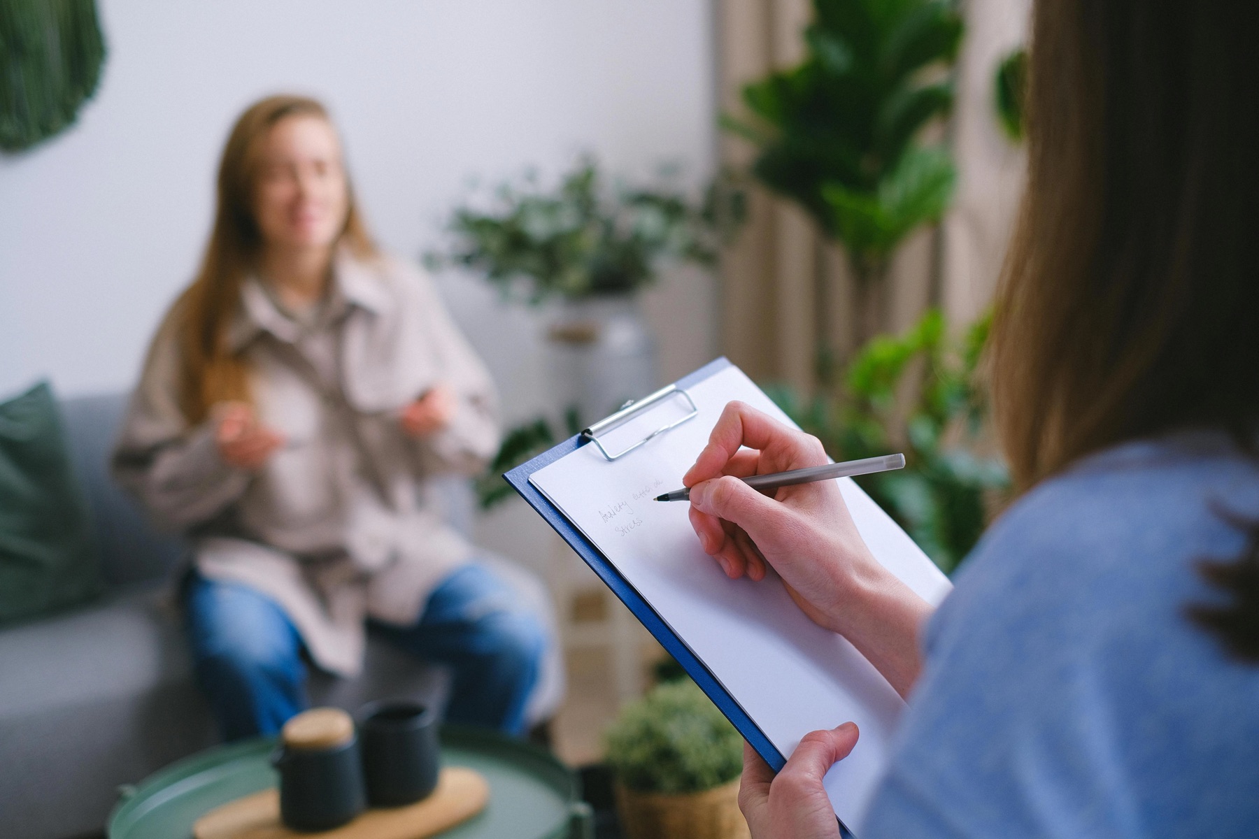 A therapist taking notes while speaking with a client